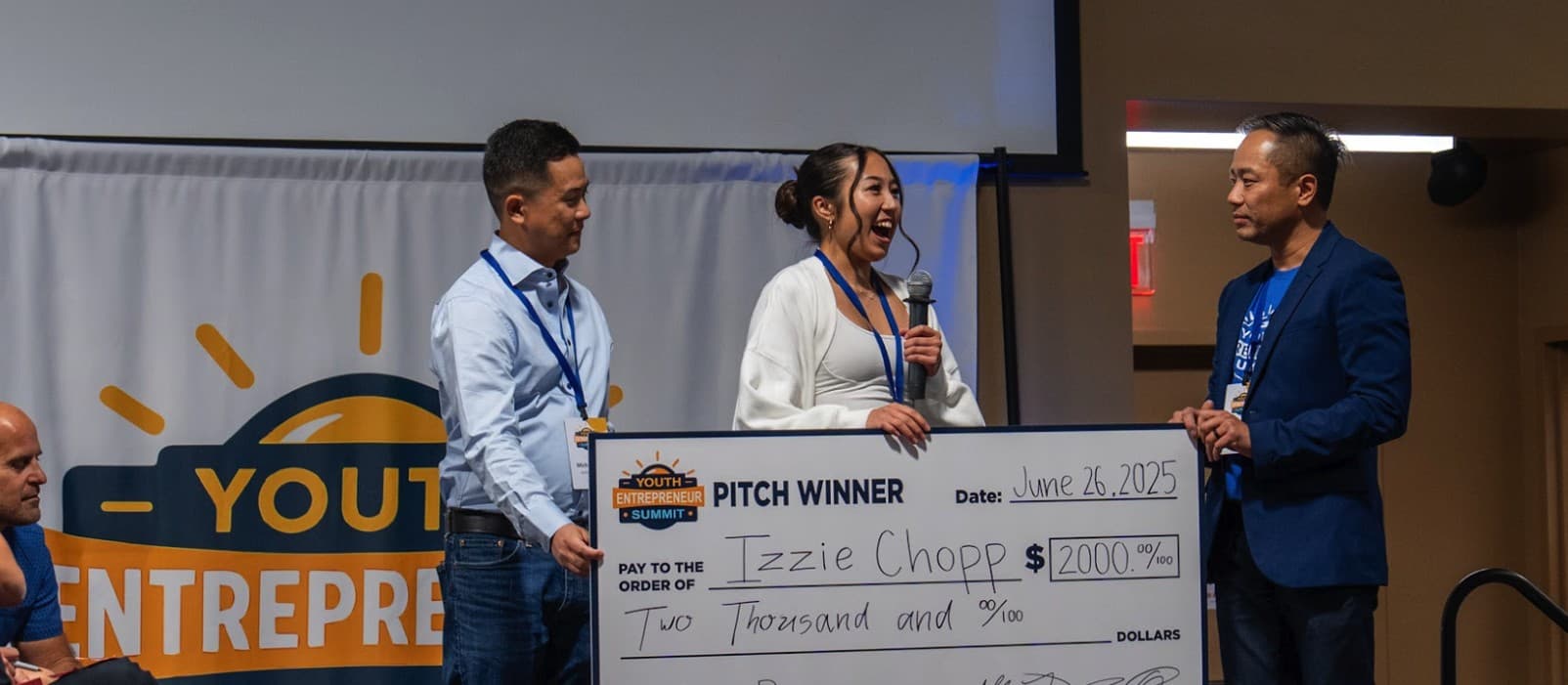 Izzie Chopp holding an oversized cheque for two thousand dollars after winning Pitch Day